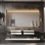 Modern bathroom with double sinks, large illuminated mirror, hanging plants, and walk-in shower.