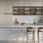 Modern kitchen with marble island, two bar stools, upper glass cabinets, and minimalist decor.