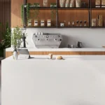 Caesarstone ICON 5112_ATERRA_BLANCA in Modern café interior with large windows, seating, coffee machine, pastries, and city skyline view.