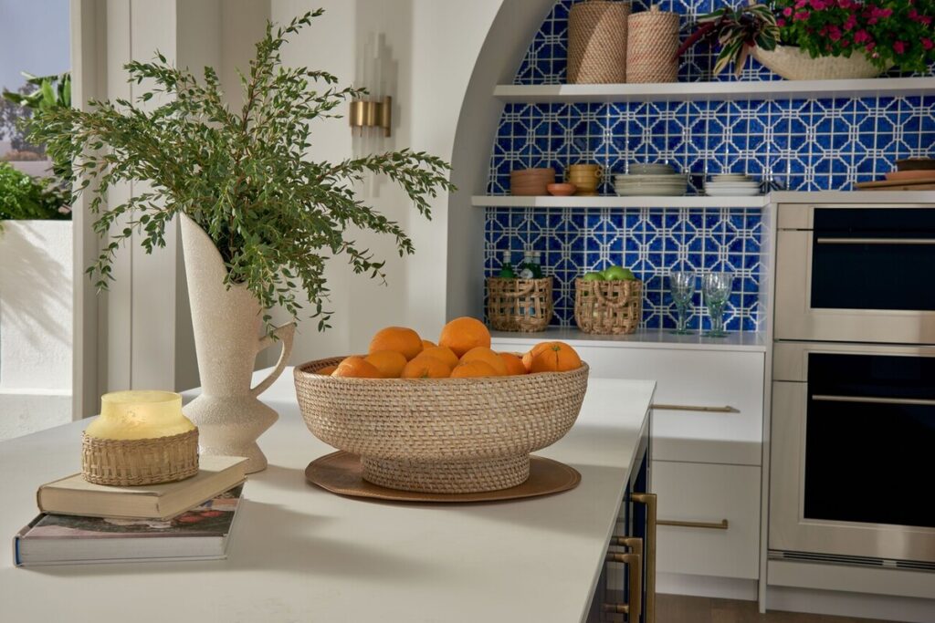 beige countertop with books, plant, and bowl of oranges