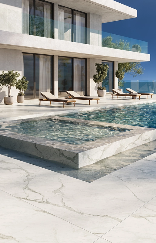 Modern luxury house with glass railings, infinity pool, loungers, and ocean view under clear sky.