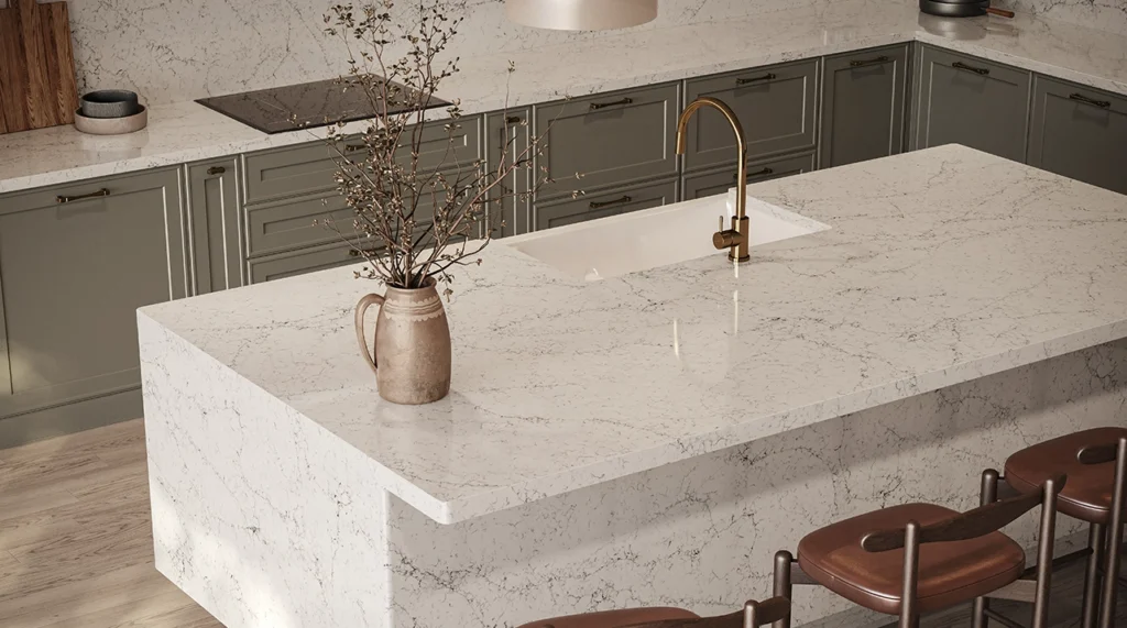 Marble kitchen island with brass faucet, brown vase, and surrounding olive-green cabinets.