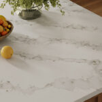 Marble countertop with a bowl of assorted fruit and a single lemon beside it.