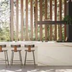 Modern kitchen with Caesarstone Porcelain 502 Sleet island, wooden bar stools, large windows, and vertical wooden slats.