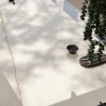 Modern kitchen Caesarstone Porcelain 502 Sleet countertop with bar stools, decorative bowls, and leafy green hanging plant.