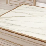 Caesarstone Porcelain 506 Mirabel countertop with gold trim on white cabinetry, accompanied by a vase with green plants.