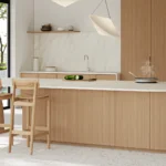 Caesarstone porcelain 506 Mirabel surface in Modern kitchen with wooden cabinetry, island, bar stools, round dining table, and large window view.
