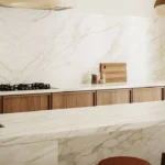 Caesarstone porcelain 506 Mirabel countertops and backsplash, wooden cabinetry, gold faucet, stovetop, and two brown stools.