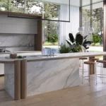 Caesarstone porcelain 506 Mirabel surface in Modern kitchen with marble island, wooden stools, large windows, and forest view outside.