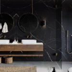 Modern black porcelain 511 smokestone bathroom with double sinks, round mirrors, woven baskets, and a walk-in shower.