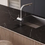 Modern kitchen countertop with black marble surface, built-in sink, sleek faucet, and two cups.