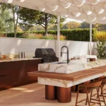 Caesarstone Porcelain 536 Antikella surface in Modern outdoor kitchen with marble-top island, wooden stools, built-in grill, and lush greenery.