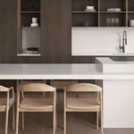 Modern kitchen with white Caesartstone 6141 Ocean Foam island, wooden chairs, open shelves, minimalist decor, and built-in sink.